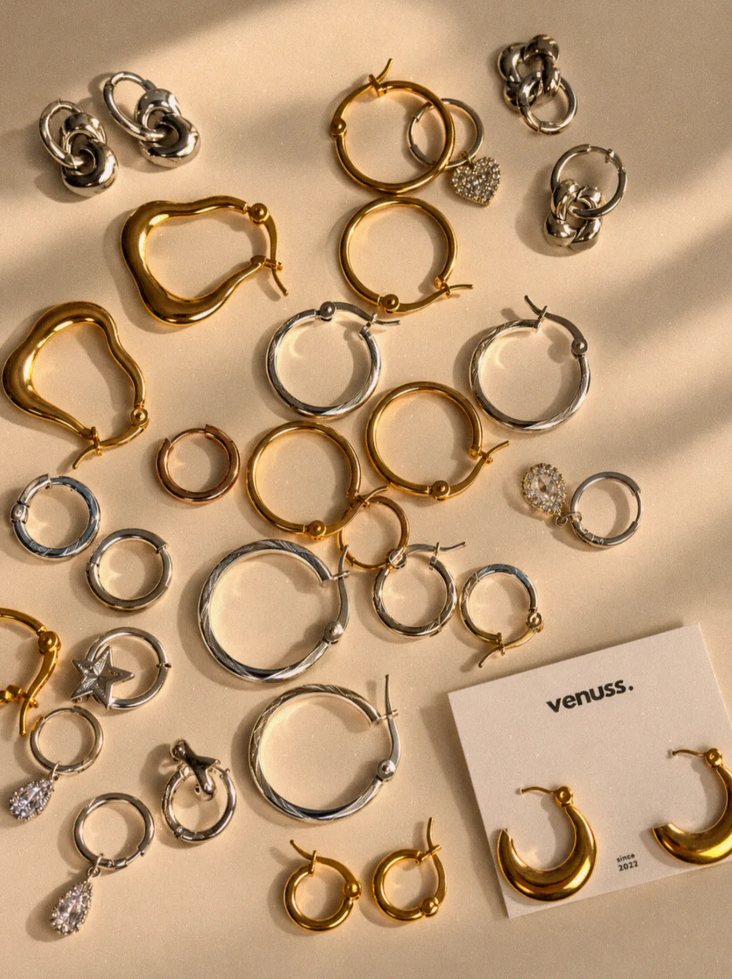 Aros y argollas de acero dorado y plateado sobre fondo arena